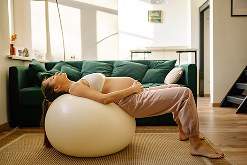Pregnant Woman Leaning On Exercise Ball in Fort Mill Home Without Advice of Chiropractor