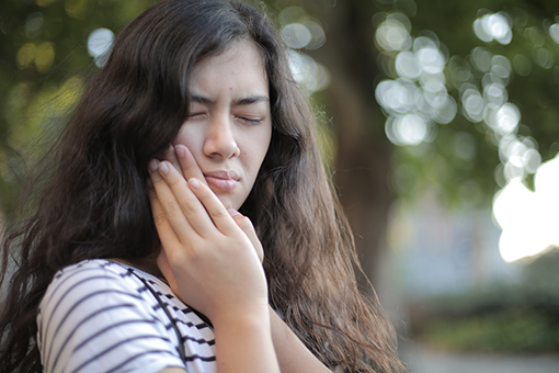 Fort Mill Woman Holding Aching Jaw In Need of TMJ Specialist and Spine Doctor